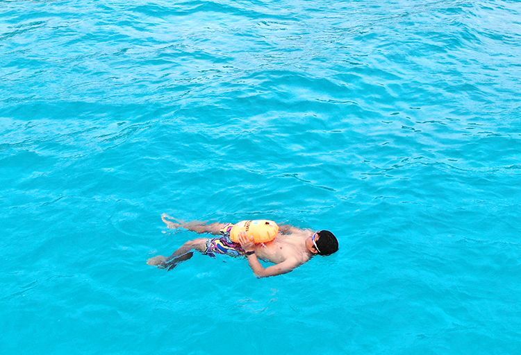 スイムブイを身に付けて沖縄の海で浮かぶ人