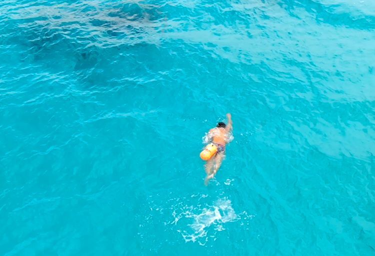 スイムブイを身に付けて沖縄の海で泳ぐ人